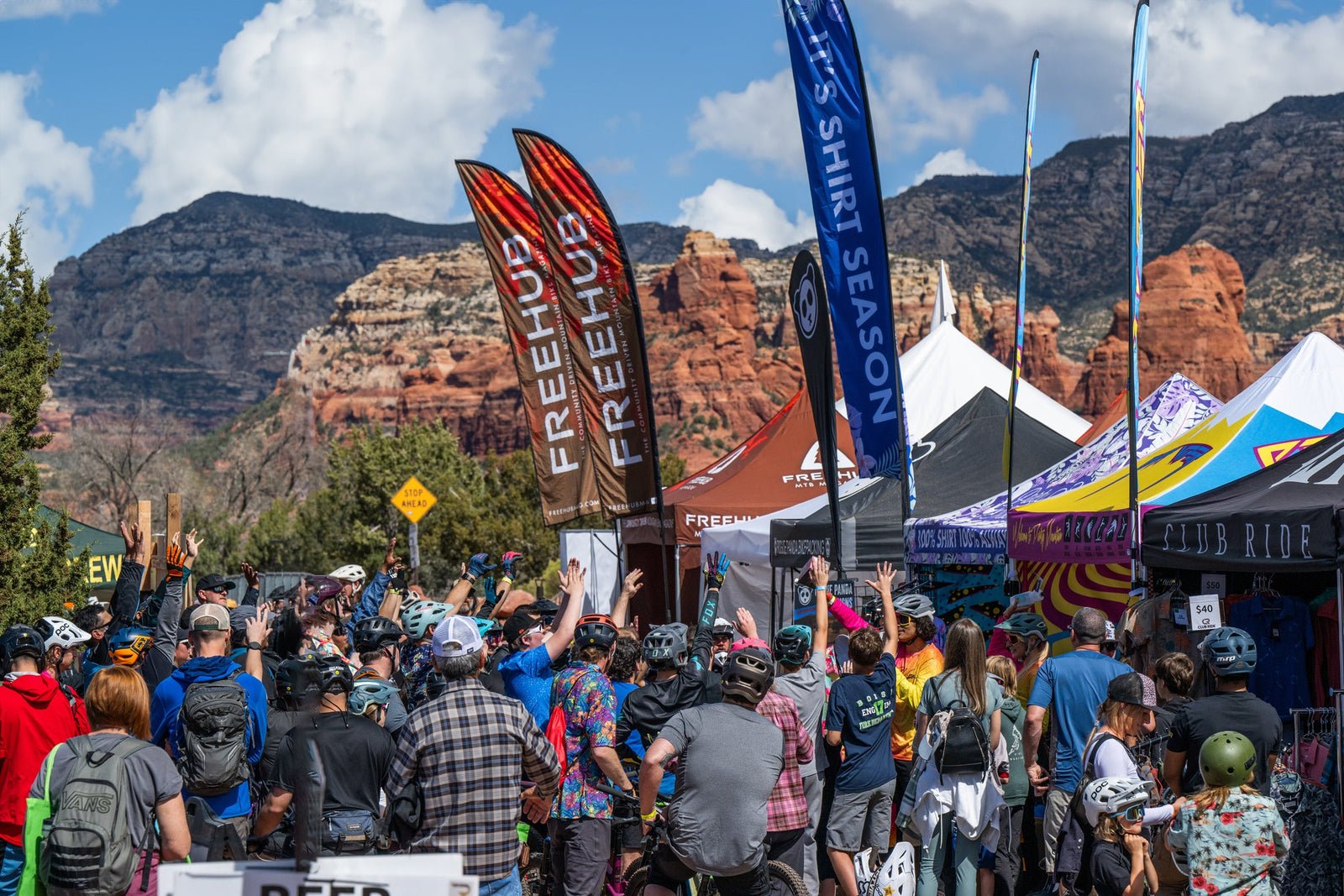 Crowd and vendor tents at the Sedona Mountain Bike Festival with red rocks behind